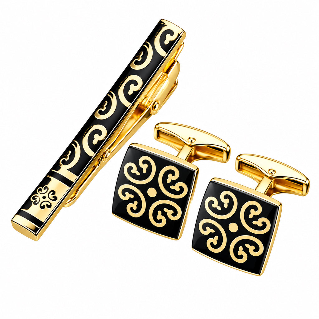 Gold-tone stainless steel cufflink set with black enamel scrollwork motif including one tie clip and two cufflinks