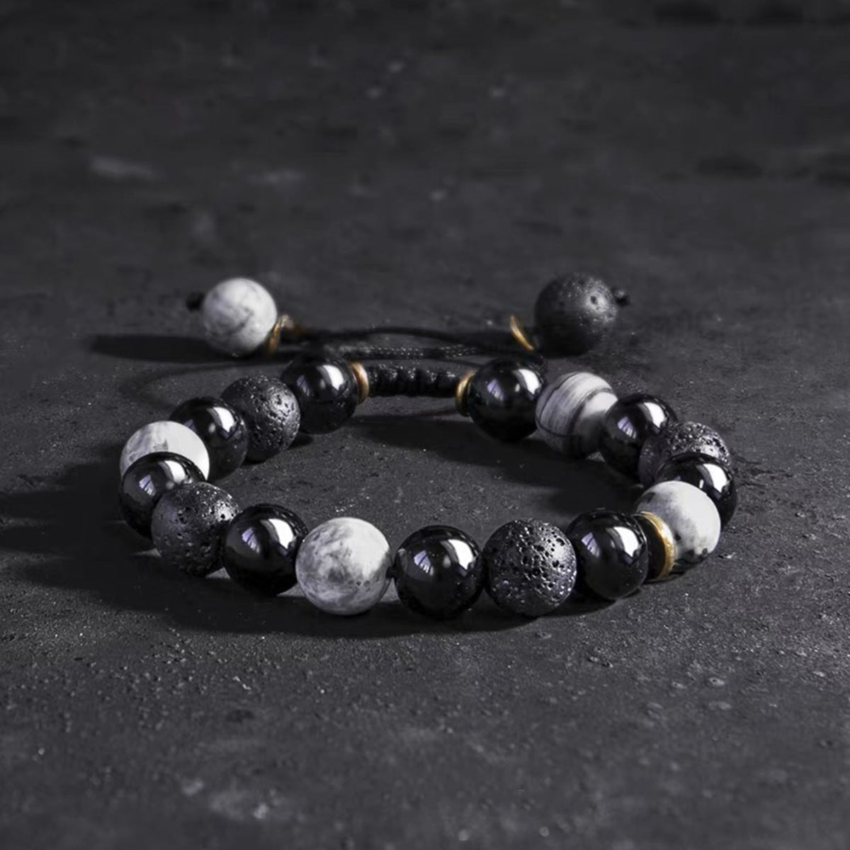 Men's bracelet featuring alternating matte black lava stones and smooth white and black agate beads with metal spacers