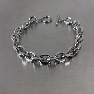 Silver-tone men's steel bracelet with chunky oval links and a toggle clasp on a neutral surface