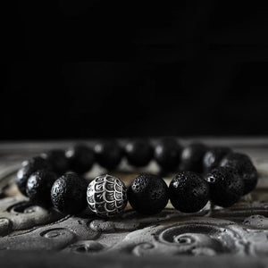 Men's lava stone bead bracelet featuring a scale-engraved silver-tone accent bead on a dark cord